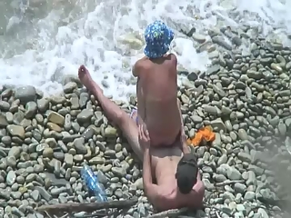 Woman rides her man's dick in rocky beach
