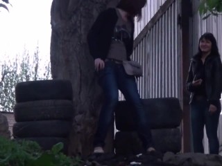 Two gals pissing next to tires